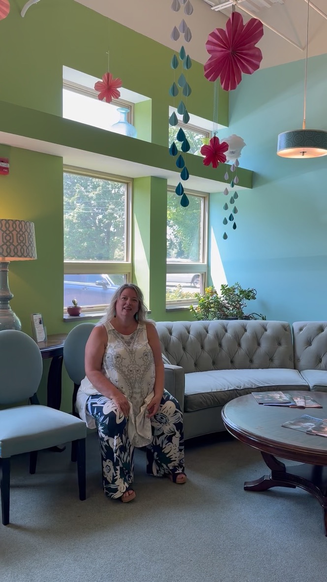 Dr. Christine Lebiecki seated in the bright reception lounge surrounded by hanging paper flowers