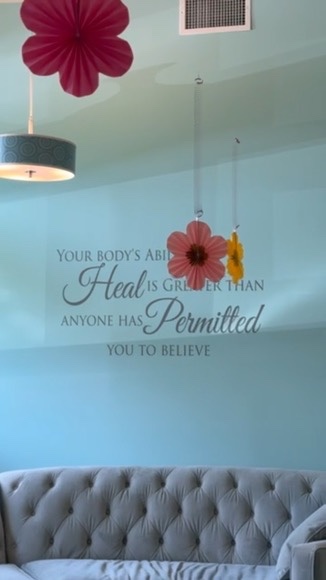 Close-up of paper flowers and a pendant lamp against the teal accent wall