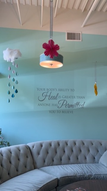Teal accent wall with a decal reading your body’s ability to heal is greater than anyone has permitted you to believe
