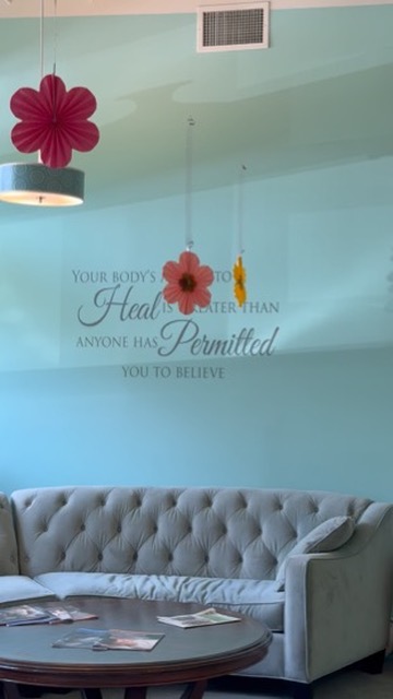 The signature teal accent wall above a grey tufted sofa